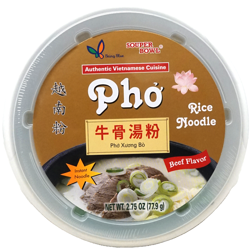 The bowl of Being Blue's Pho Beef Flavor Rice Noodle Soup contains thin rice noodles in a rich, beef-flavored broth. It is topped with slices of tender beef and garnished with fresh green onions, adding a touch of color and freshness to the dish. The presentation is inviting and appetizing, showcasing the hearty and traditional elements of Vietnamese pho.